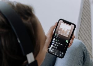 ragazzo con telefono in mano che ascolta musica su Spotify del Vincitore Sanremo 2026