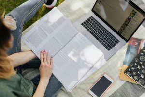 ragazza che studia davanti un c con un libro tra le mani - Conciliare studio e lavoro